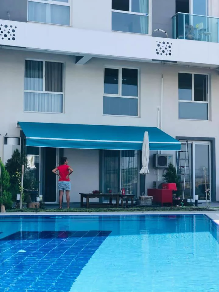 Havuz kenarında turkuaz mafsallı tente uygulaması